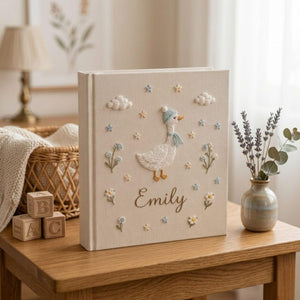 Personalized goose hand embroidered baby photo album with pastel balloons and floral meadow design on linen cover
