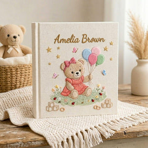 Personalized hand embroidered photo album featuring teddy bear holding pastel balloons surrounded by flowers butterflies and custom baby name