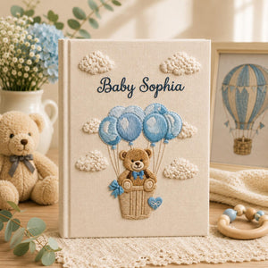 Personalized embroidered baby photo album with teddy bear in balloon basket and blue cloud nursery design