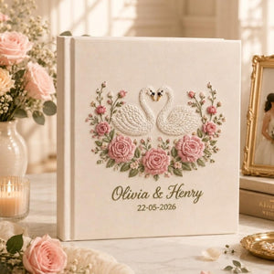 Personalized embroidered wedding photo album with white swans, pink rose floral embroidery, custom couple names, wedding date, and elegant linen hardcover design