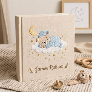 Personalized hand embroidered photo album featuring a sleeping teddy bear on a cloud beneath a crescent moon with custom name embroidery