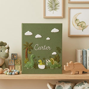 Personalized dinosaur hand embroidered baby photo album with cute prehistoric nursery design on green linen cover