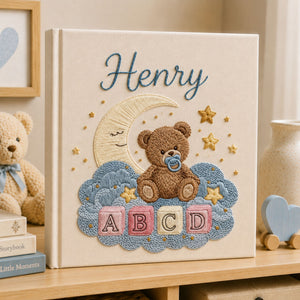 Personalized hand embroidered photo album featuring a teddy bear with a pacifier sitting on clouds beneath a crescent moon with colorful ABC blocks and stars