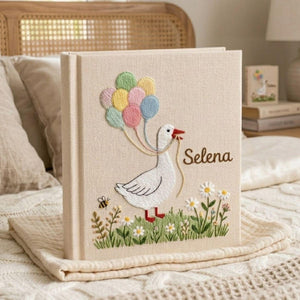 Personalized goose hand embroidered baby photo album with pastel balloons and floral meadow design on linen cover