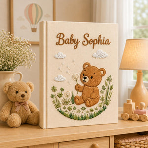 Personalized embroidered baby photo album with teddy bear holding dandelion flower in whimsical meadow setting