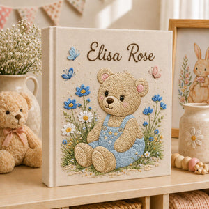 Personalized hand embroidered baby photo album with teddy bear in blue overalls surrounded by flowers and butterflies