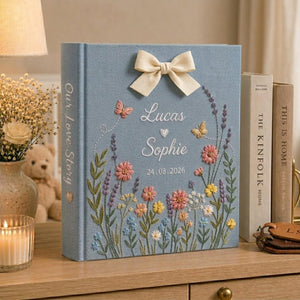 Personalized embroidered floral couple photo album with butterflies, custom names, ribbon bow, and romantic wildflower design on blue linen cover