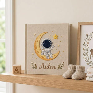 Personalized hand embroidered baby photo album with astronaut sitting on crescent moon and stars nursery design