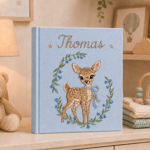 Personalized hand embroidered photo album featuring a woodland fawn surrounded by blue wildflowers and custom name embroidery