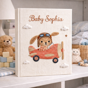 Personalized hand embroidered photo album featuring a bunny flying a purple airplane with heart-shaped balloons and fluffy clouds