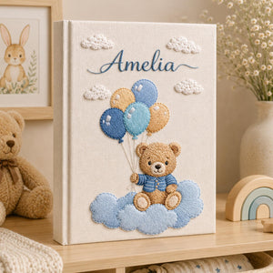 Personalized hand embroidered baby photo album with teddy bear holding blue balloons on clouds