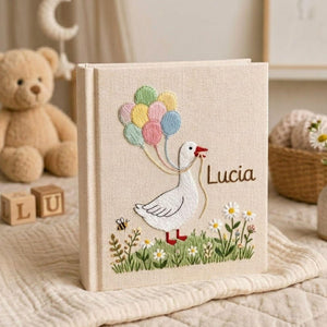 Personalized goose hand embroidered baby photo album with pastel balloons and floral meadow design on linen cover
