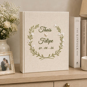 Neutral floral embroidered wedding albums with ivory roses, botanical wreaths, geometric floral frames, and personalized couple names on linen covers