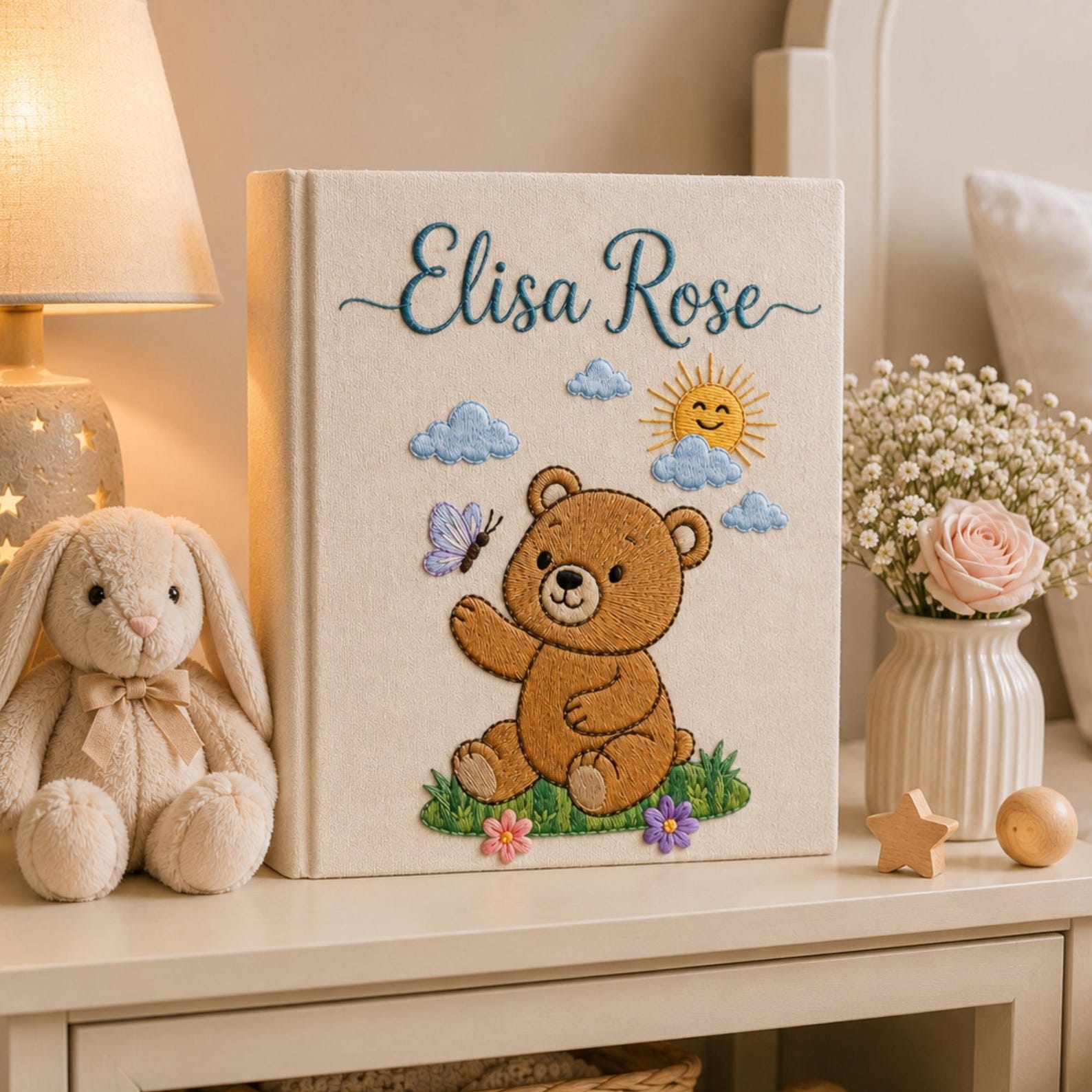 Personalized embroidered baby photo album featuring teddy bear, sunshine, clouds, flowers, and butterfly design