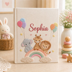 Personalized hand embroidered photo album featuring giraffe, elephant, lion, rainbow, balloons, clouds and stars on a linen cover