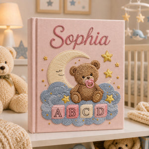 Personalized hand embroidered photo album featuring a teddy bear with a pacifier sitting on clouds beneath a crescent moon with colorful ABC blocks and stars