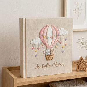 Personalized hand embroidered photo album featuring an elephant and bunny in a pastel hot air balloon with hanging hearts and custom name embroidery