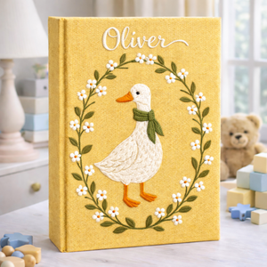 Personalized hand embroidered photo album featuring a white goose surrounded by a floral wreath on a yellow linen cover