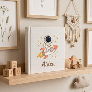 Personalized hand embroidered baby photo album with astronaut riding rocket and stars nursery design