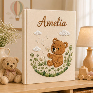 Personalized embroidered baby photo album with teddy bear holding dandelion flower in whimsical meadow setting