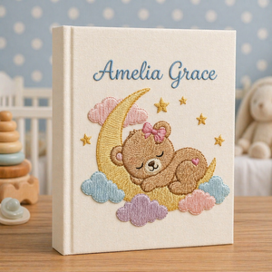 Personalized hand embroidered photo album featuring a dreamland night sky scene with crescent moon, sleeping teddy bear, stars, clouds and custom name embroidery