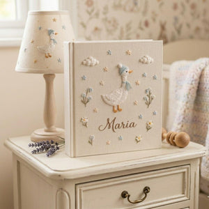 Personalized goose hand embroidered baby photo album with pastel balloons and floral meadow design on linen cover