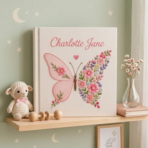 Personalized hand embroidered photo album featuring a floral butterfly with pink wildflowers, lavender accents, and custom name embroidery on a premium linen cover