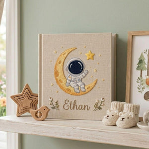 Personalized hand embroidered baby photo album with astronaut sitting on crescent moon and stars nursery design