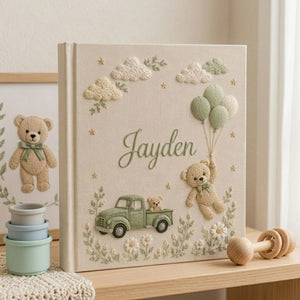 Personalized hand embroidered photo album featuring a vintage sage green pickup truck, floating teddy bear with balloons, clouds, and wildflowers on a premium linen cover customized with a baby name