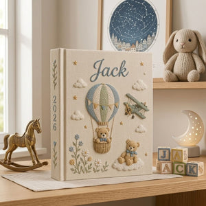 Personalized hand embroidered photo album featuring a teddy bear in a vintage hot air balloon with a classic biplane, clouds, stars, wildflowers, custom name and year embroidery on a premium linen cover