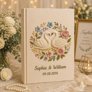 Personalized embroidered wedding photo album with floral swan embroidery, pastel botanical flowers, custom names, wedding date, and linen hardcover design