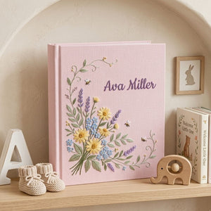 Personalized hand embroidered photo album featuring a wildflower bouquet with lavender, daisies, delicate greenery, bees, and custom name embroidery on a blue linen cover