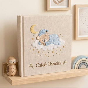 Personalized hand embroidered photo album featuring a sleeping teddy bear on a cloud beneath a crescent moon with custom name embroidery
