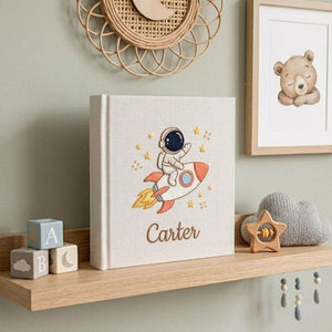 Personalized hand embroidered baby photo album with astronaut riding rocket and stars nursery design