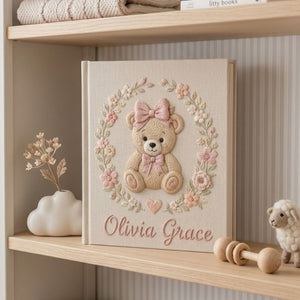 Personalized hand embroidered photo album featuring a classic teddy bear with pink bows and delicate floral embroidery on a linen cover