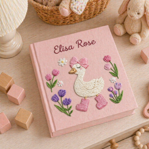 Personalized hand embroidered photo album featuring a charming goose girl with bow, flowers, and cottagecore details on a pink linen cover