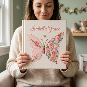 Personalized hand embroidered photo album featuring a floral butterfly with pink wildflowers, lavender accents, and custom name embroidery on a premium linen cover