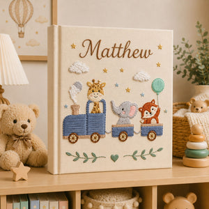 Personalized hand embroidered photo album featuring a safari animal train with giraffe, hippo, lion and zebra on a linen cover