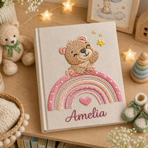 Personalized hand embroidered baby photo album featuring teddy bear sitting on pastel rainbow with stars and heart accents