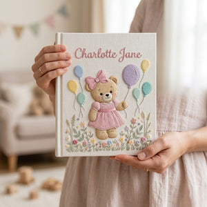 Personalized hand embroidered photo album featuring a birthday teddy bear holding pastel balloons in a blooming flower garden
