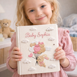 Personalized hand embroidered photo album featuring a bunny holding pastel heart balloons floating among fluffy clouds