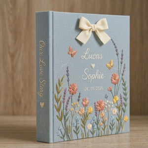 Personalized embroidered floral couple photo album with butterflies, custom names, ribbon bow, and romantic wildflower design on blue linen cover