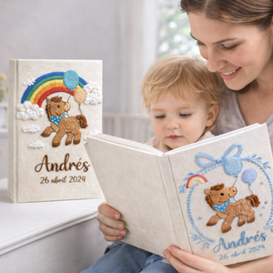 Personalized hand embroidered photo album featuring an adorable pony with balloons, colorful rainbow, fluffy clouds, and custom name embroidery on linen cover