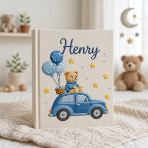 Personalized hand embroidered baby photo album featuring teddy bear riding a blue vintage car with balloons and stars on linen cover