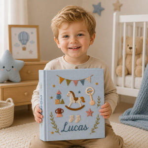 Personalized hand embroidered baby photo album with rocking horse, baby rattle, bunting flags, and vintage nursery toys