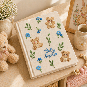 Personalized hand embroidered photo album featuring teddy bears, botanical flowers, leafy accents and custom baby name embroidery on a linen cover