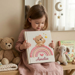 Personalized hand embroidered baby photo album featuring teddy bear sitting on pastel rainbow with stars and heart accents