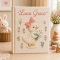 Personalized hand embroidered photo album featuring a cute duckling with a polka dot bow holding a daisy bouquet surrounded by pastel flowers and custom name embroidery