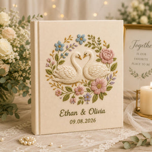 Personalized embroidered wedding photo album with floral swan embroidery, pastel botanical flowers, custom names, wedding date, and linen hardcover design