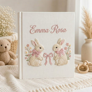 Personalized hand embroidered photo album featuring two adorable rabbits with pink bows and delicate floral accents on a linen cover